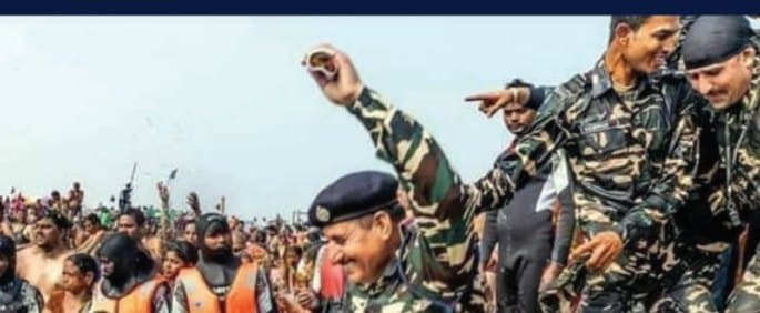Army personnel cheering among a crowd at the riverbank, with people in orange life jackets in the foreground