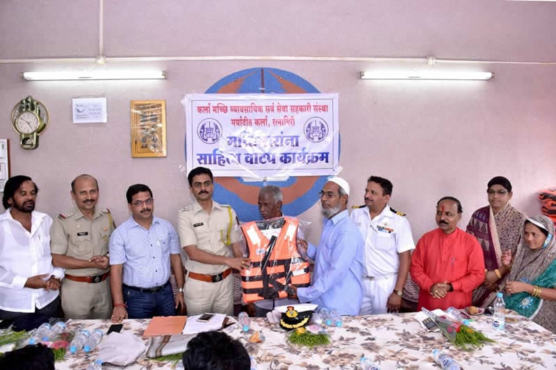 A life jacket being handed over at the same distribution, officials standing behind the table