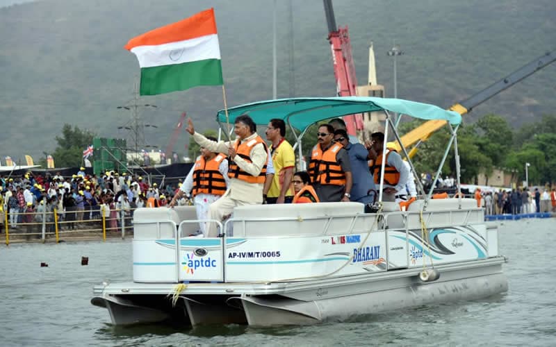 A boat carrying the national flag, crew in MM life jackets, crowd ashore