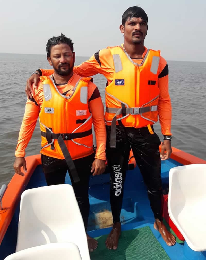 Two lifeguards in MM life jackets standing in a boat at sea