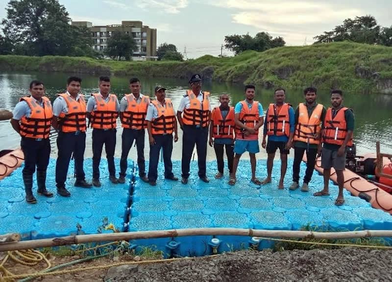 A crew lined up on a floating platform in MM life jackets