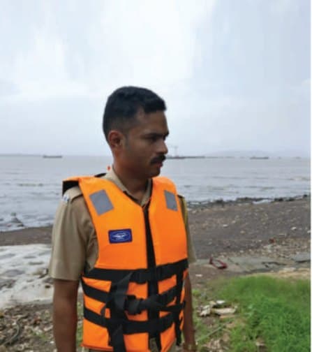 A marine police officer in an MM life jacket on the shore