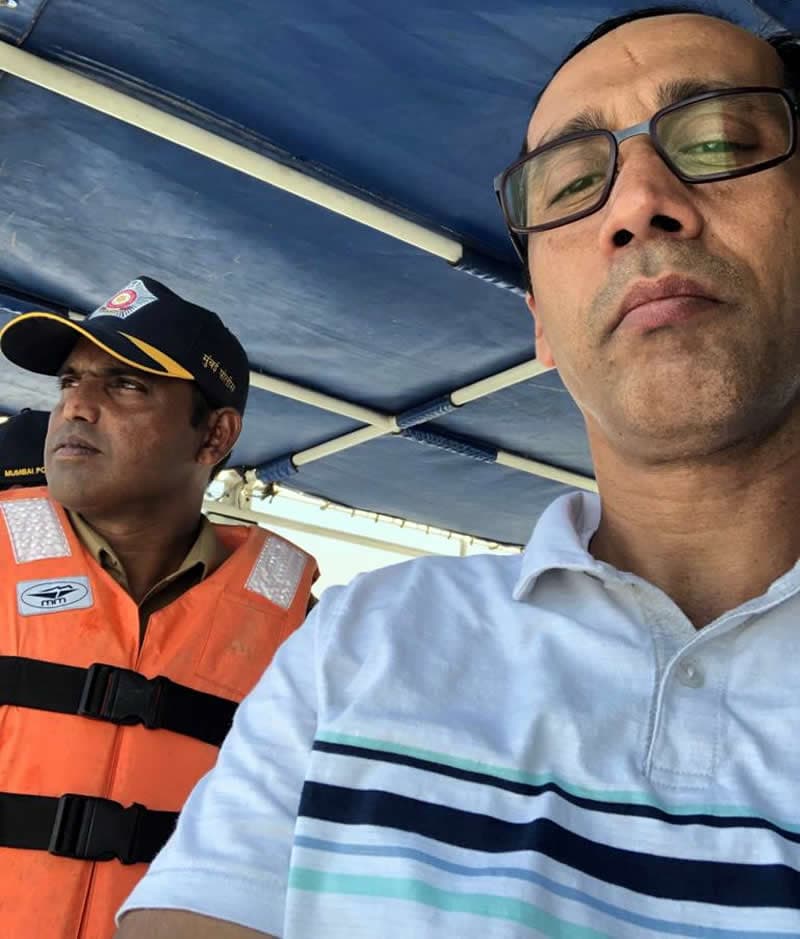 A marine police officer in an MM life jacket aboard a launch, beside a passenger